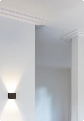 Gestrichene Wand mit Deckenprofil und Wandleuchte